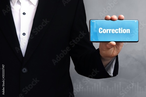 Correction. Businessman holding a phone in his hand. Man present screen with word. Blue Background. Business, Finance, Statistics, Analysis, Economy