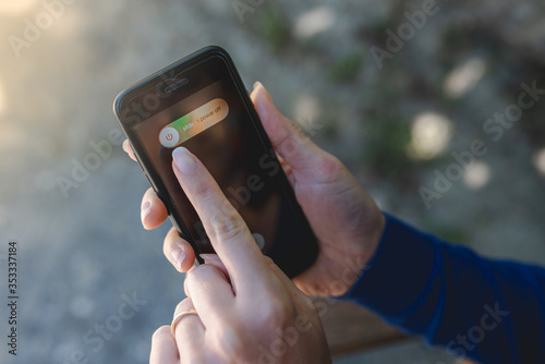 Close up woman hands holding a smartphone with background in wild nature. Turning off the device to detoxifying from a long period using technology during Coronavirus quarantine.  photo