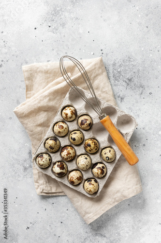 Eggs on a tray on the kitchen table. Quail eggs and a whisk for baking. Eggs and whisk on a culinary background. Concept of preparation for baking. Top view with space for text