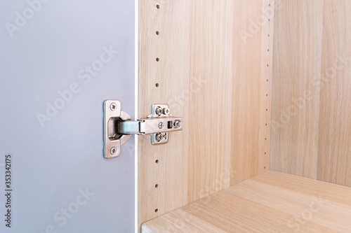 Polished Stainless door hinge on a cabinet door for interior design.