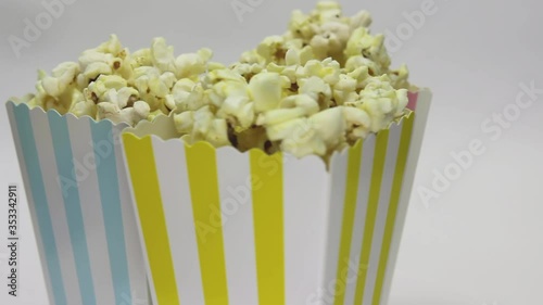 Three striped popcorn bags full of pop corn rotating on white background