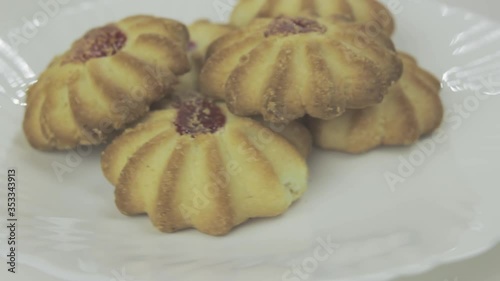Fresh shortbread cookies with fruit jam rotating on a white plate