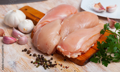 Raw  uncooked chicken breast fillet with garlic and greens