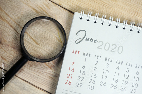 June 2020 calender with magnifying glass on white background. Selective Focus 