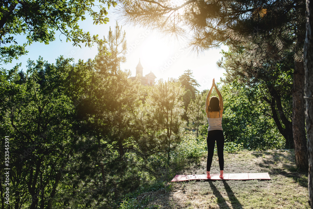 Young woman doing stretching pilates exercises in a garden on the grass. Open air sport activities and healthy lifestyle concept. Young woman doing stretching pilates exercises in a garden on the grass. Open air sport activities and healthy lifestyle concept.