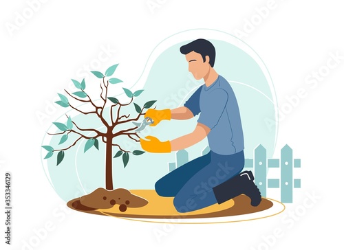 Man is cutting tree branches on his backyard in gloves and boots near the fence. Outdoor gardening hobby or profession. Exterior in modern city private house. Cozy and calming leisure activity.