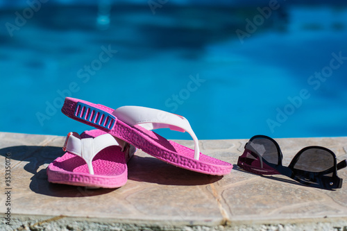 Flip flops and sunglasses on the edge of the pool. Summer concept.