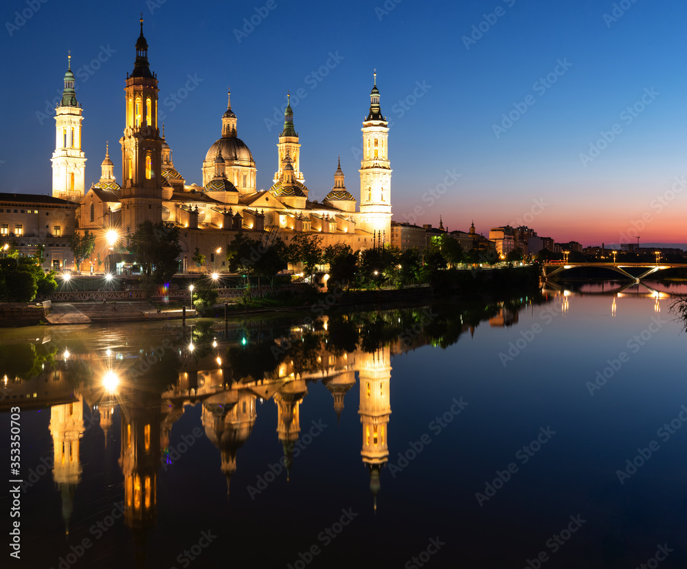 Illuminated Basilica of Our Lady of the Pillar on the banks of the Ebro at sunset in Zaragoza, Spain