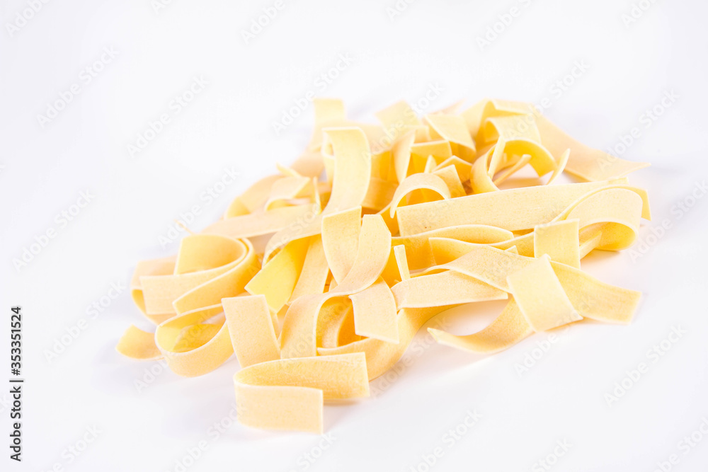 Raw pappardelle pasta on a white background