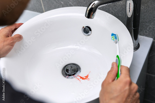 man have bleeding gums while brushing the teeth. tooth decay and gingvitis concept photo