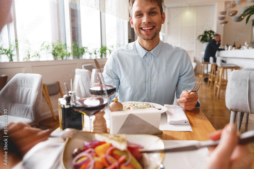 Cheerful young man having dinner with friend in cafe Cheerful young man having dinner with friend in cafe