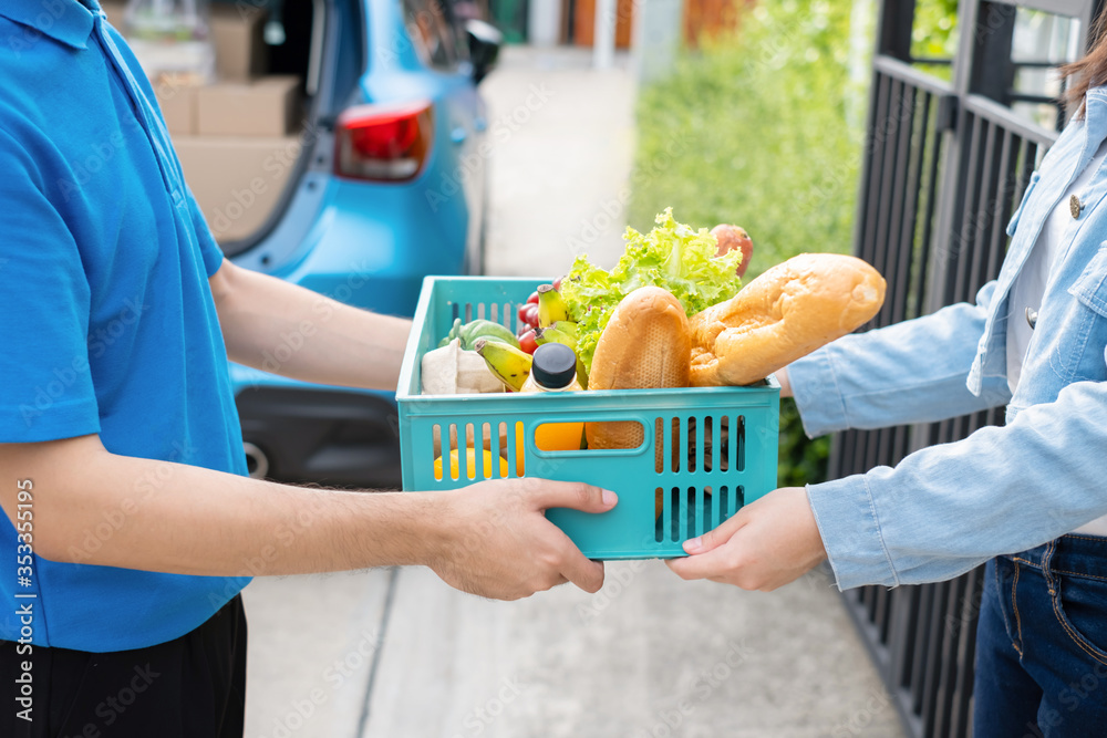 Food Deliver Asian man in blue uniform give fruit and vegetable to receiver customer front house, fast express grocery service when crisis coronavirus, covid19 new normal lifestyle concept. Food Deliver Asian man in blue uniform give fruit and vegetable to receiver customer front house, fast express grocery service when crisis coronavirus, covid19 new normal lifestyle concept.