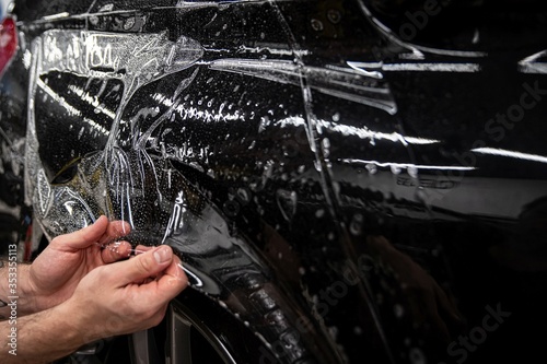 Obraz na płótnie Car wrappping. Man car detailing studio worker appling transparent protection foil on car body. w salonie