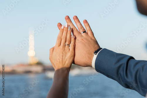 Hands of the bride and groom with wedding rings in the sun