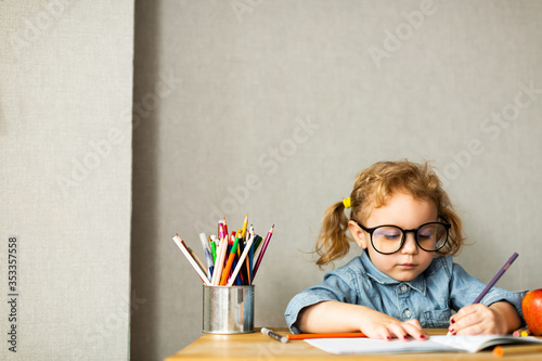 Cute European girl sits at school desk, concept of learning, back to school