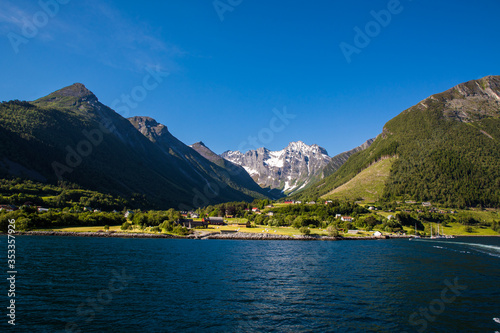 Picturesque scene of Urke village and Hjorundfjorden fjord, Norway. Drammatic sky and gloomy mountains. Landscape.