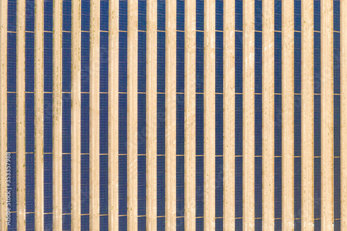 Vertical aerial view of a photovoltaic solar panel farm producing sustainable renewable energy in a desert power plant.