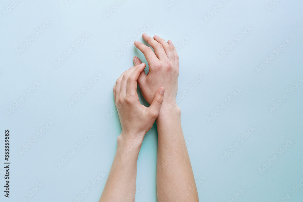 Tender female hands lie calmly on a light blue table. Tender female hands lie calmly on a light blue table.