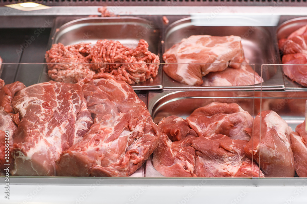 Heap of fresh meat food meat food background in supermarket store. Different types of raw meat in plastic boxes, leg of lamb on the bone, beef tail, beef neck, beef blade. Concept of farm and raw