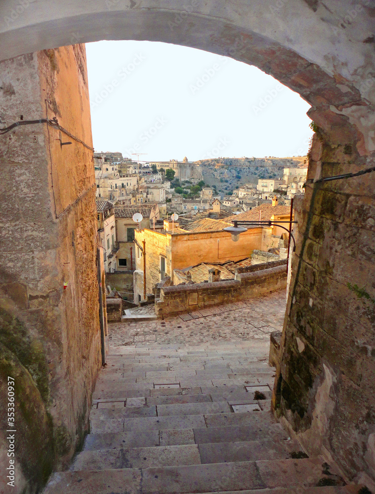 Detail of narrow street and stone arch in the ancient town of Matera (Sassi di Matera), European Capital of Culture 2019,and UNESCO Heritage  site and clouds, Basilicata Italy     