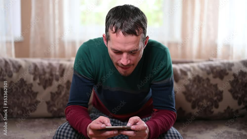 A man sits on a sofa and plays on the phone at home A man sits on a sofa and plays on the phone at home