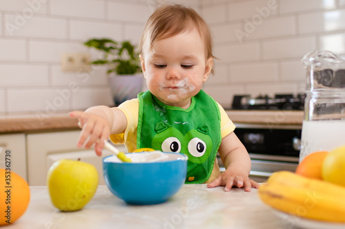 Happy child girl in the kitchen eats a delicious cottage cheese and porridge.