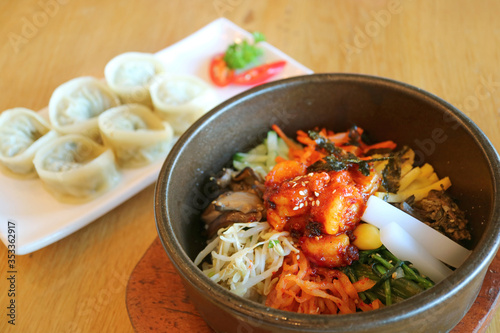 Mouthwatering Bibimbap or Korean Mixed Rice Bowl with Blurry Mandu Dumplings in Background