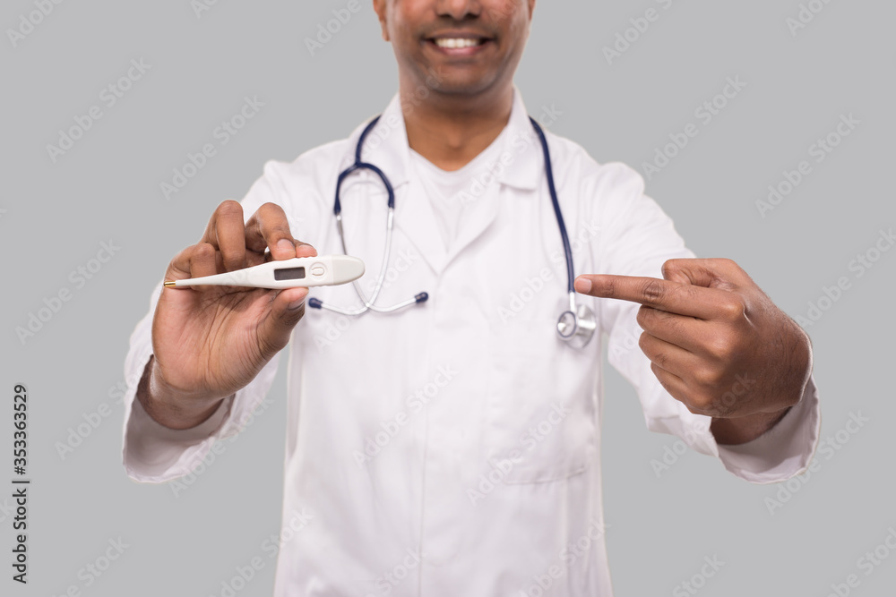 Doctor Pointing at Thermometer Isolated. Indian Man Doctor Smiling with Thermometer in Hands. Healthy Life, Doctor, Virus Concept Doctor Pointing at Thermometer Isolated. Indian Man Doctor Smiling with Thermometer in Hands. Healthy Life, Doctor, Virus Concept