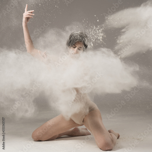 Fototapeta Naklejka Na Ścianę i Meble -  Graceful woman dancing in a cloud of dust