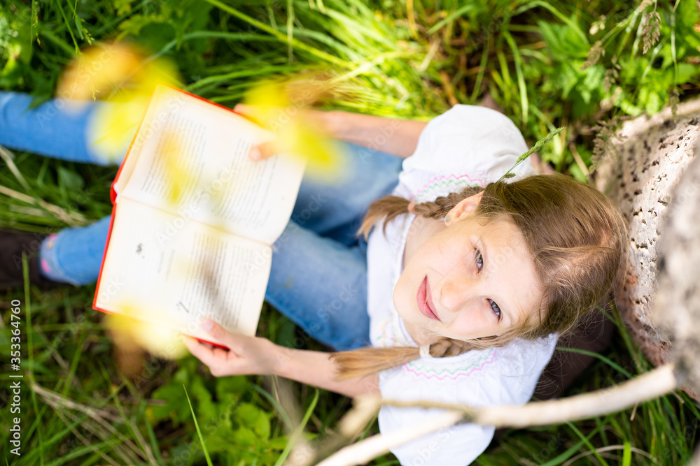 Teenage girl in white T-shirt sitting by the tree in the forest and ...