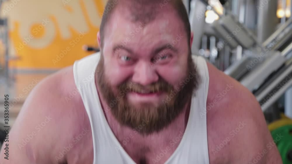 A large and powerful weightlifter lifts the barbell and is very tense. A large and powerful weightlifter lifts the barbell and is very tense.