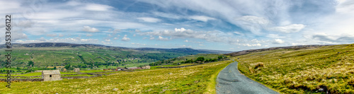 a panorama of hills of the Yorkshire Dales with lone stone building and blue sky with clouds photo