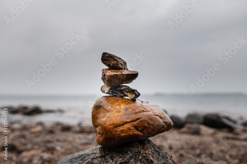 Wet stacked stones on shoreline in foggy weather and rain