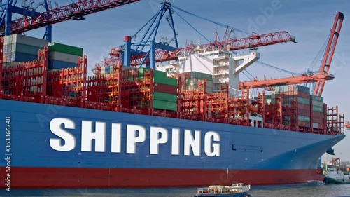 Container ship is being loaded in a harbor. The lettering 