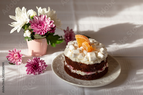 Freshly baked homemade chocolate cake with cream cheese and cherry and marshmallow on top.