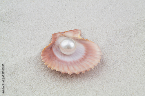 Pearl in seashell on white sand background
