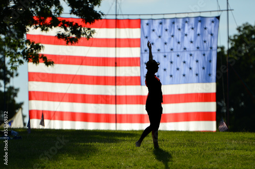The Silhouette of a young woman l in front of huge United States National Flag erected in National Gardens Park in Washington DC during Memorial weekend