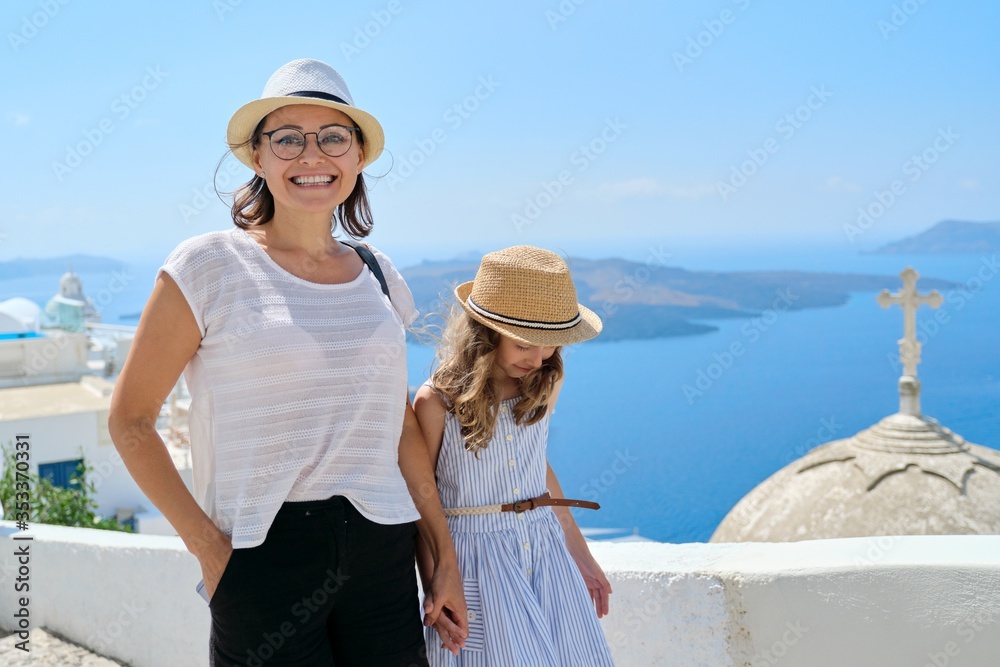 Mother and daughter child walking together on famous tourist island of Santorini