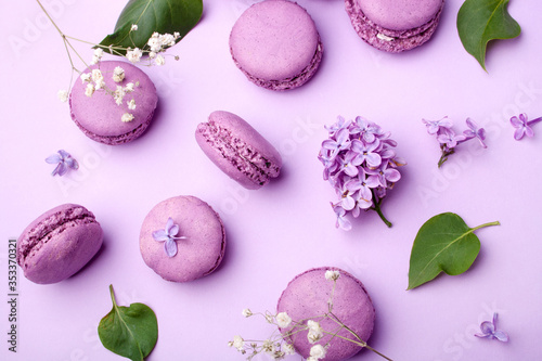 Lilac macarons and lilac flowers on a pastel lilac background. Delicious dessert. Flat lay style. Home cooking