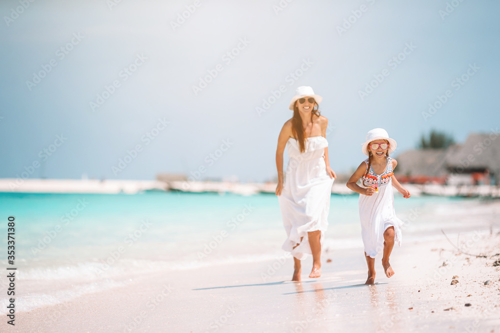 Beautiful mother and daughter at Caribbean beach enjoying summer vacation.