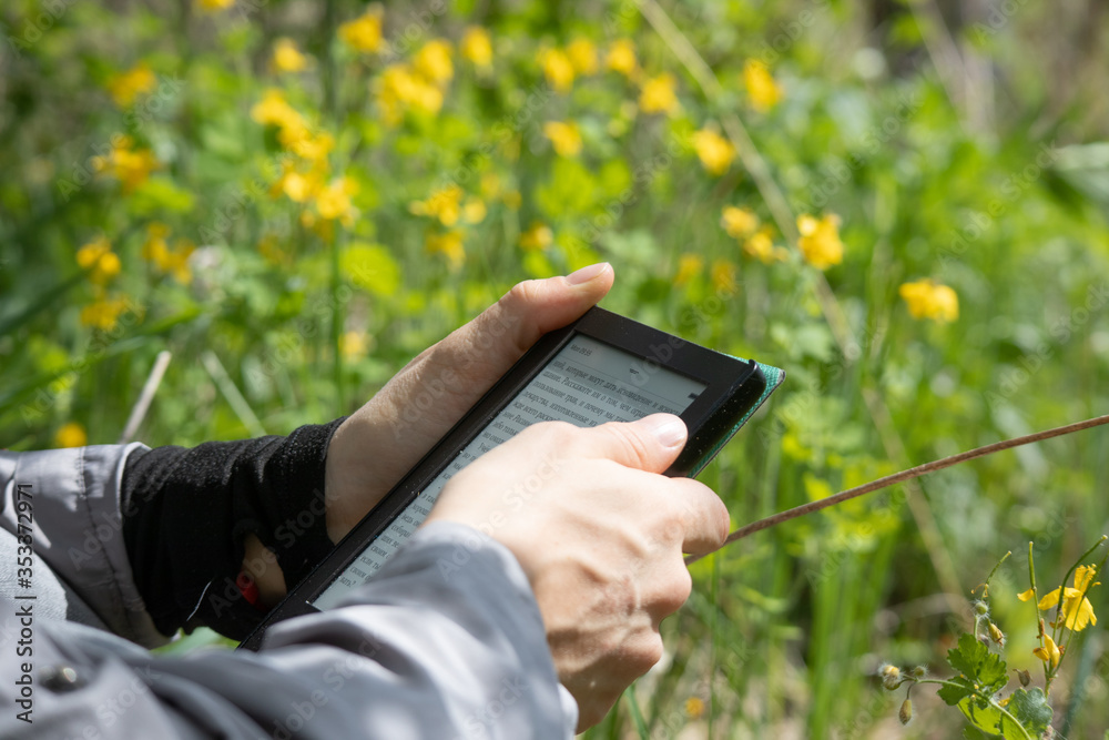 Young woman reading an ebook in nature