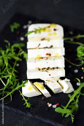 Selective focus. Feta cheese on a stone board with olive oil and seasonings.