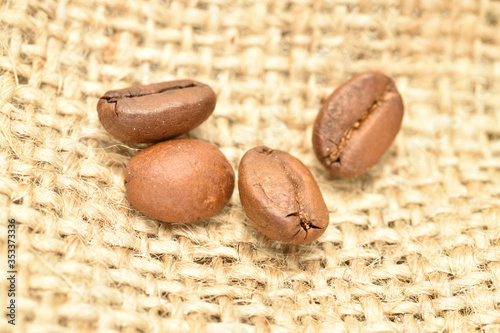 Fragrant roasted coffee grains, close-up, on jute fabric.