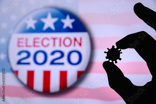 Hand silhouette hold covid 19 virus. Logo of USA presidental Election 2020 in background. US presidential elections are threatened by coronavirus and may be postponed photo