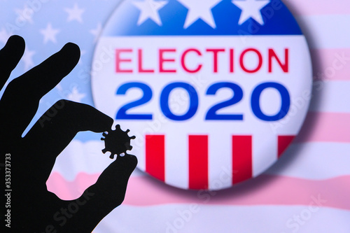Hand silhouette hold covid 19 virus. Logo of USA presidental Election 2020 in background. US presidential elections are threatened by coronavirus and may be postponed photo