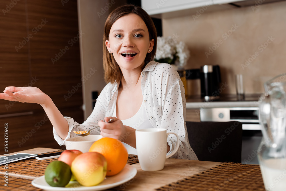selective focus of excited woman holding spoon with corn flakes near fruits selective focus of excited woman holding spoon with corn flakes near fruits