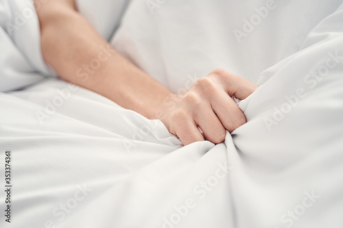 Female hand lying on the crumpled duvet