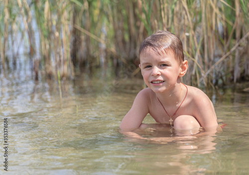 Fototapeta Naklejka Na Ścianę i Meble -  Happy little boy is swimming in the lake