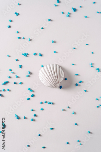 White sea shell surrounded by blue sand on bright background  Summer time concept
