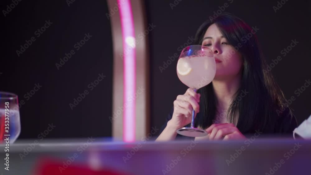 Sexy Asian woman drinking cocktail alone covid-19 style, lady wear mask at nightclub bar, purple light, new normal life during covid-19, female sipping on cocktail, slow motion, drinking distance